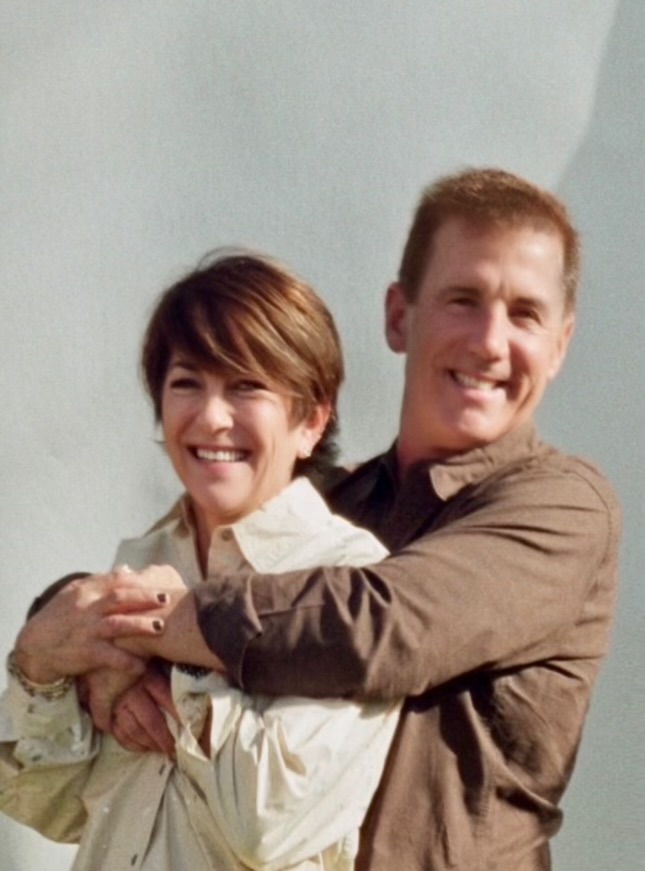 A man and woman stand closely together, sharing a warm smile. The man hugs the woman from behind against a plain, light-colored backdrop, perfectly capturing the essence of "Opposites Align" in this heartwarming moment from Episode 2. - Nuovo Salon Group in Sarasota & Bradenton, FL