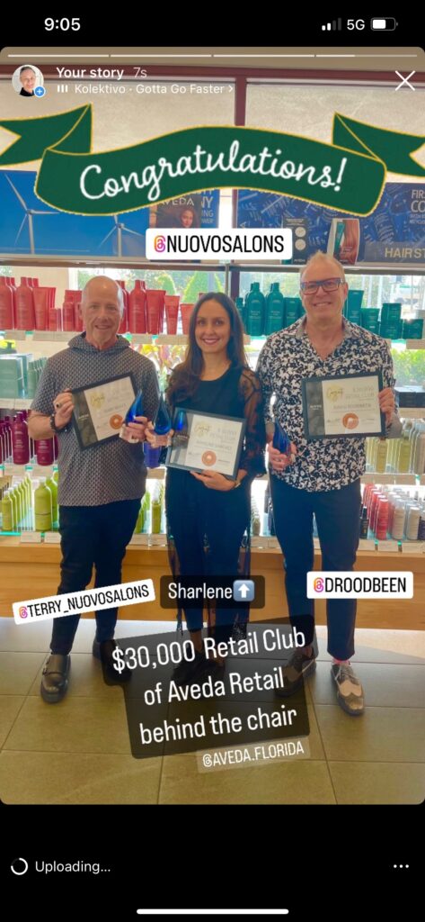 Three people stand in front of salon products, each holding a certificate and trophy, with signs indicating a $30,000 Retail Club award at Aveda Retail in Florida. - Nuovo Salon Group in Sarasota & Bradenton, FL