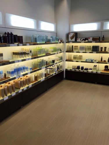 Shelves in a store display various bottles and containers of hair and skincare products in a well-lit, organized setting. - Nuovo Salon Group in Sarasota & Bradenton, FL