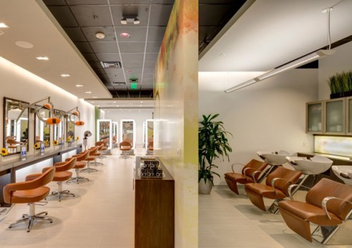 Modern hair salon interior with brown styling chairs on the left, wash stations on the right, large mirrors, and bright lighting. - Nuovo Salon Group in Sarasota & Bradenton, FL
